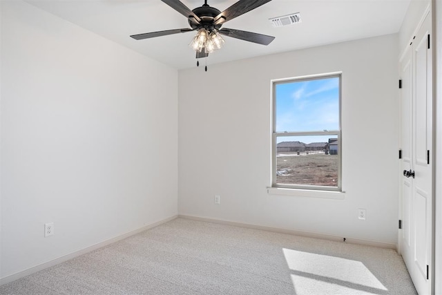 spare room with light carpet, baseboards, visible vents, and a ceiling fan