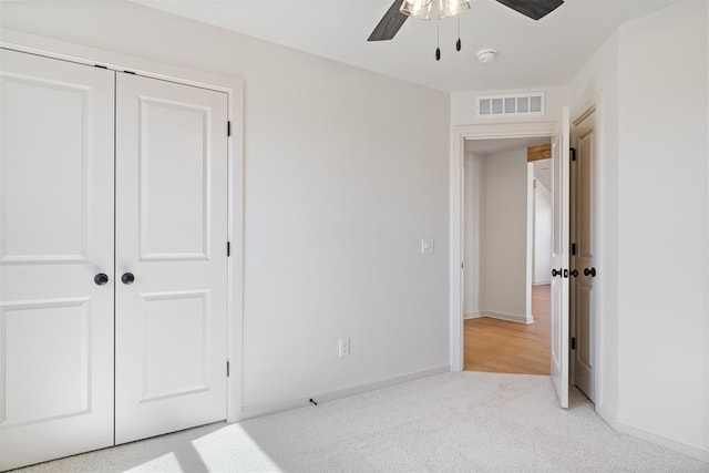 unfurnished bedroom featuring light colored carpet, a closet, visible vents, and baseboards