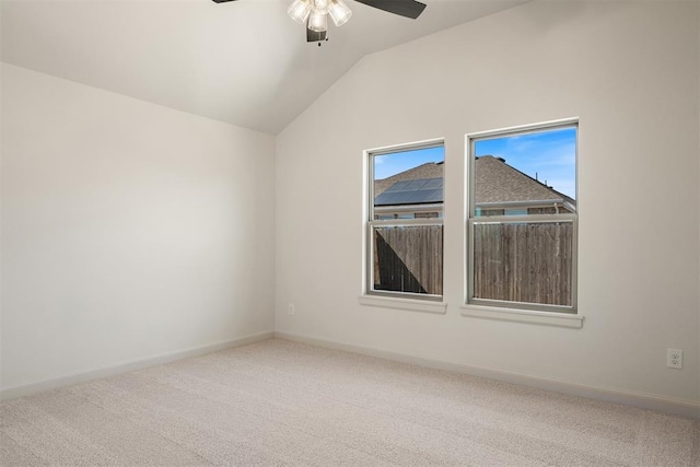 empty room with lofted ceiling, ceiling fan, carpet, and baseboards