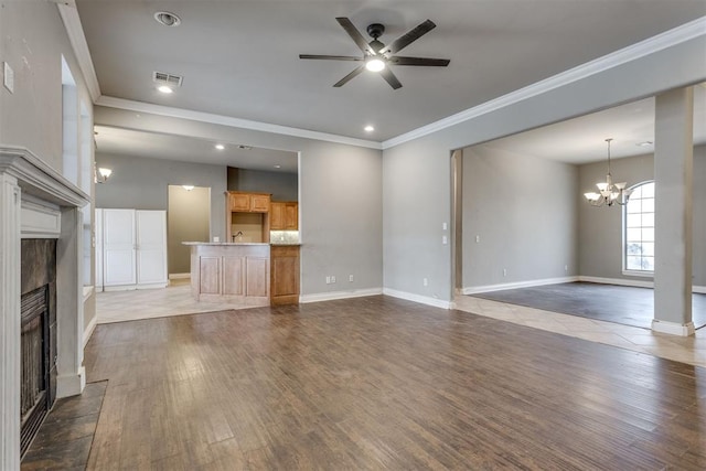 unfurnished living room featuring dark hardwood / wood-style flooring, crown molding, ceiling fan with notable chandelier, and a fireplace