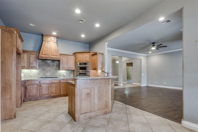 kitchen featuring premium range hood, light stone counters, light tile patterned floors, appliances with stainless steel finishes, and ceiling fan