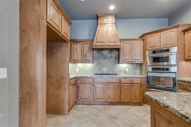 kitchen featuring light stone countertops, decorative backsplash, stainless steel appliances, and light tile patterned floors