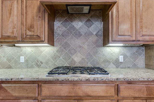 kitchen featuring stainless steel gas cooktop, backsplash, and light stone counters