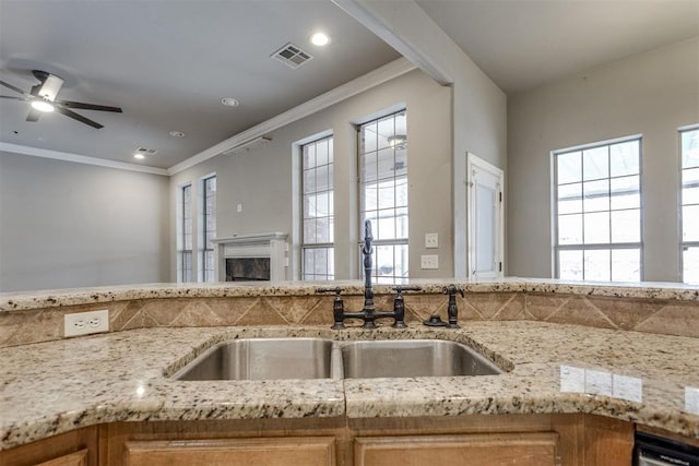 kitchen featuring crown molding, sink, light stone counters, and ceiling fan