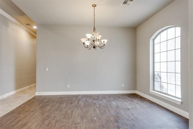 spare room featuring hardwood / wood-style flooring and an inviting chandelier