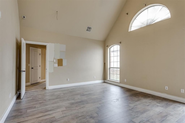 spare room with light hardwood / wood-style flooring and high vaulted ceiling