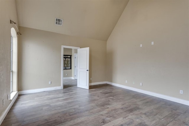 unfurnished room with hardwood / wood-style floors and high vaulted ceiling