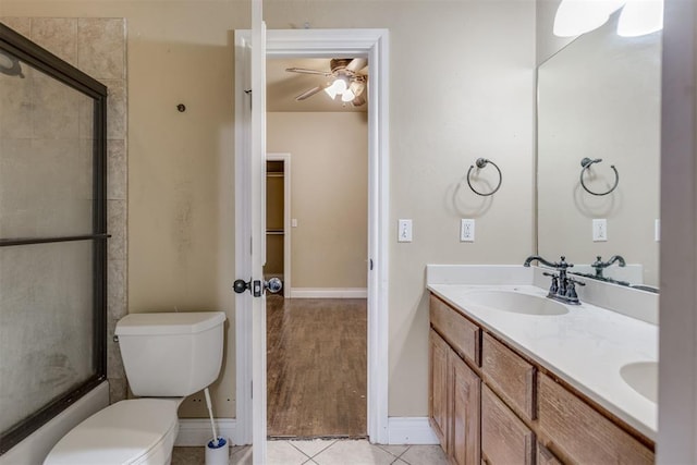 full bathroom featuring shower / bath combination with glass door, tile patterned flooring, vanity, ceiling fan, and toilet