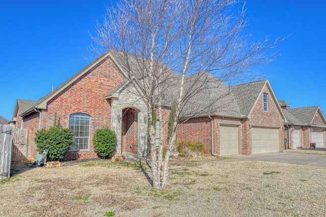 view of front of home with driveway, a front yard, a shingled roof, a garage, and brick siding