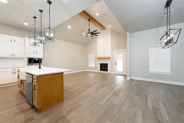 kitchen with decorative light fixtures, white cabinetry, stainless steel dishwasher, a center island with sink, and beam ceiling