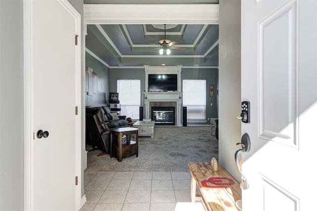 living room with ceiling fan, light colored carpet, ornamental molding, and a tray ceiling