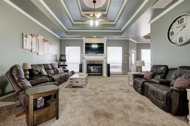 carpeted living room with ornamental molding, ceiling fan, and a tray ceiling