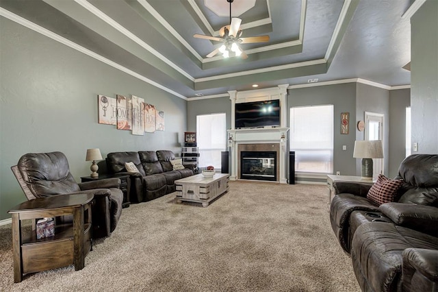 living room with a raised ceiling, crown molding, carpet floors, and ceiling fan