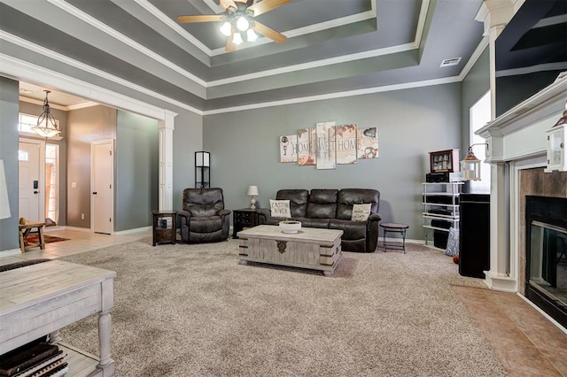 carpeted living room with ornate columns, ornamental molding, ceiling fan, a high end fireplace, and a raised ceiling