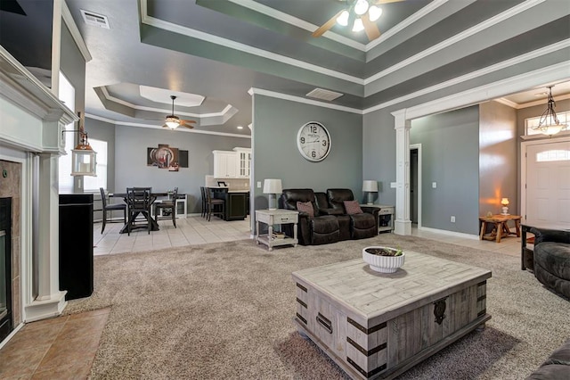 carpeted living room featuring ceiling fan, ornamental molding, a tray ceiling, and a fireplace