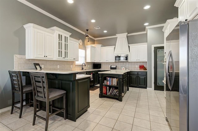 kitchen featuring a kitchen island, white cabinets, a kitchen bar, light tile patterned floors, and stainless steel appliances