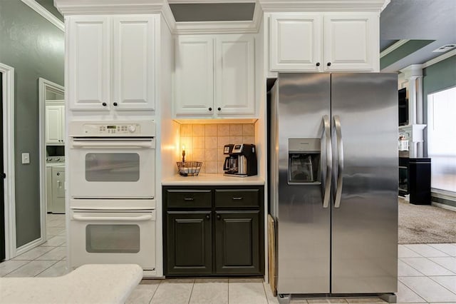 kitchen featuring white cabinetry, light tile patterned floors, stainless steel fridge, and white double oven