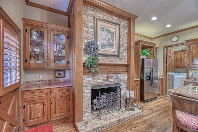 3225 Cotswold Sq, Norman, OK 73072 - kitchen featuring independent washer and dryer, stainless steel refrigerator with ice dispenser, a fireplace, ornamental molding, and light wood-type flooring