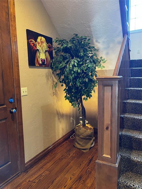 3225 Cotswold Sq, Norman, OK 73072 - staircase featuring hardwood / wood-style floors, vaulted ceiling, and a textured ceiling