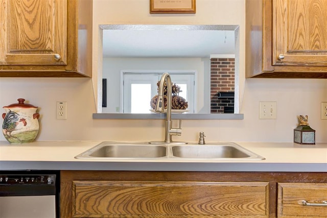 kitchen featuring dishwasher, light countertops, brown cabinetry, and a sink