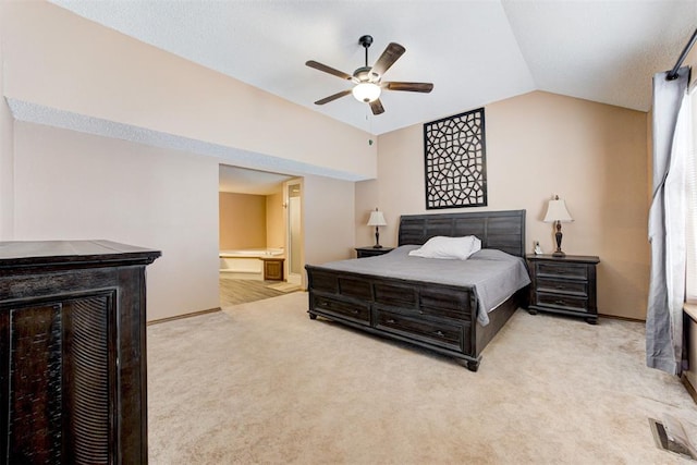 bedroom with light colored carpet, visible vents, a ceiling fan, vaulted ceiling, and ensuite bath