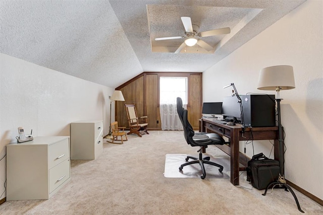 office space featuring light colored carpet, a ceiling fan, vaulted ceiling, a textured ceiling, and baseboards