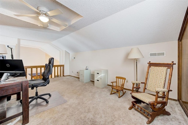 office area with a textured ceiling, light carpet, visible vents, baseboards, and vaulted ceiling