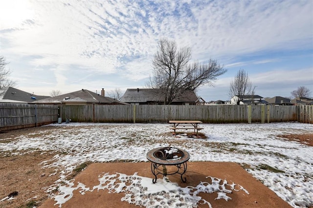 yard layered in snow with an outdoor fire pit and a fenced backyard