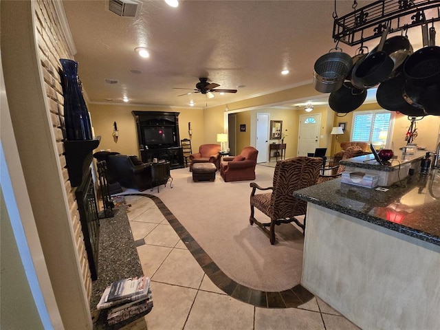 tiled living room with ornamental molding and ceiling fan