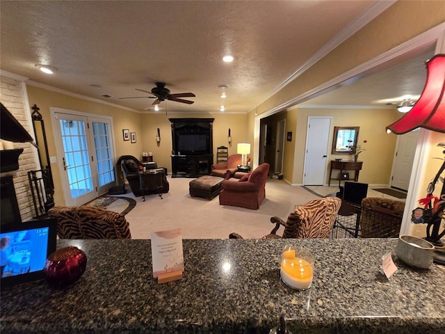 carpeted living room featuring crown molding, ceiling fan, a fireplace, and a textured ceiling