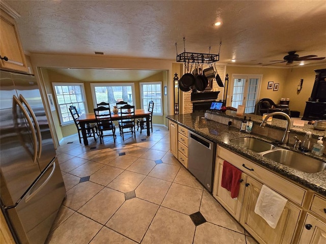 kitchen with light brown cabinetry, sink, dark stone counters, light tile patterned floors, and stainless steel appliances