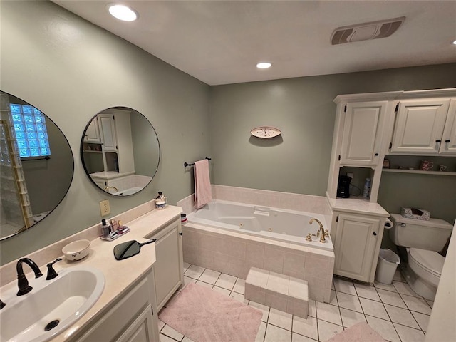 bathroom with tile patterned flooring, vanity, tiled bath, and toilet