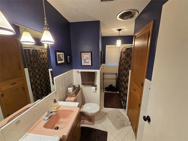 bathroom with tile patterned flooring, vanity, tile walls, and toilet