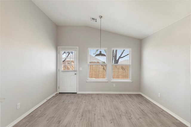 unfurnished dining area featuring vaulted ceiling, a wealth of natural light, and light hardwood / wood-style flooring