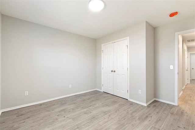 unfurnished bedroom featuring a closet and light wood-type flooring