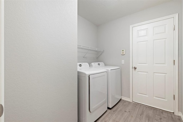 laundry area with washing machine and dryer and light hardwood / wood-style floors