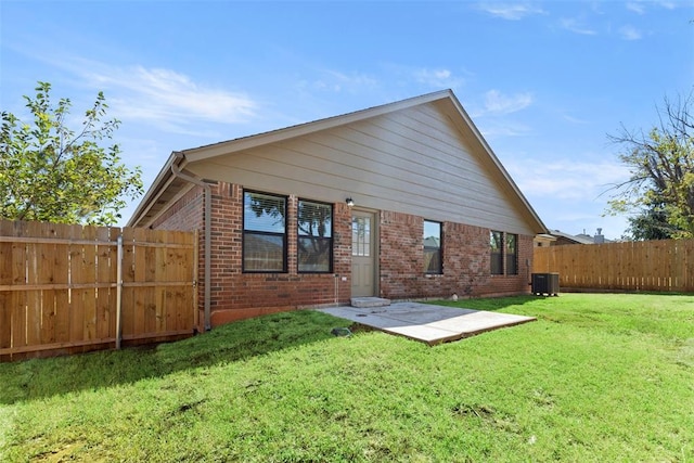 rear view of house with cooling unit, a patio area, and a lawn