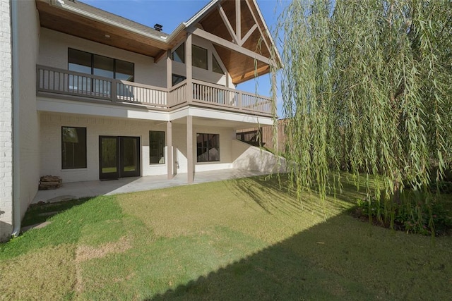 rear view of property featuring a yard, a patio area, and a balcony