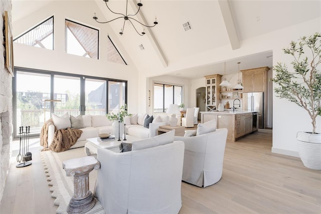 living room featuring sink, a chandelier, high vaulted ceiling, light hardwood / wood-style flooring, and beamed ceiling