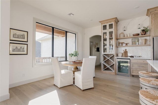 dining space with wine cooler, bar area, and light hardwood / wood-style flooring