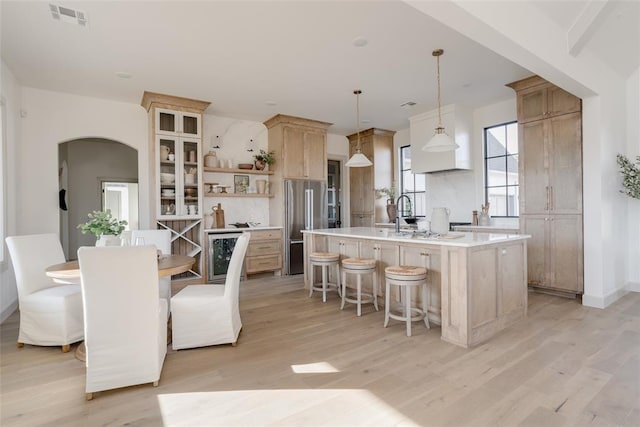 kitchen with sink, a breakfast bar area, a center island with sink, light wood-type flooring, and pendant lighting