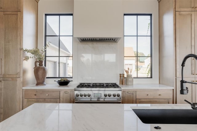 kitchen featuring stove, a wealth of natural light, and light brown cabinets