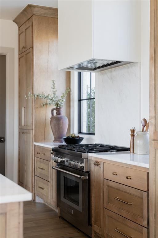 kitchen with high end range, light brown cabinetry, custom exhaust hood, and wood-type flooring