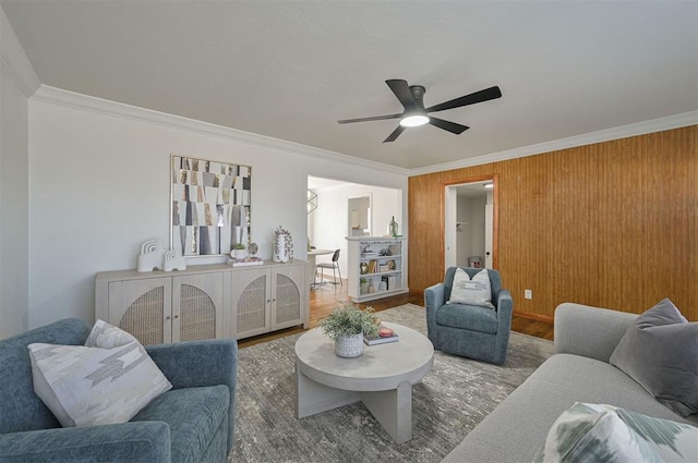 living room with wood-type flooring, ornamental molding, and ceiling fan