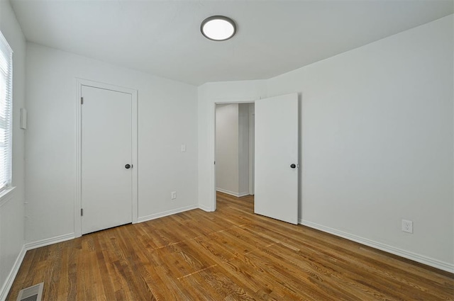 unfurnished bedroom with multiple windows and hardwood / wood-style flooring