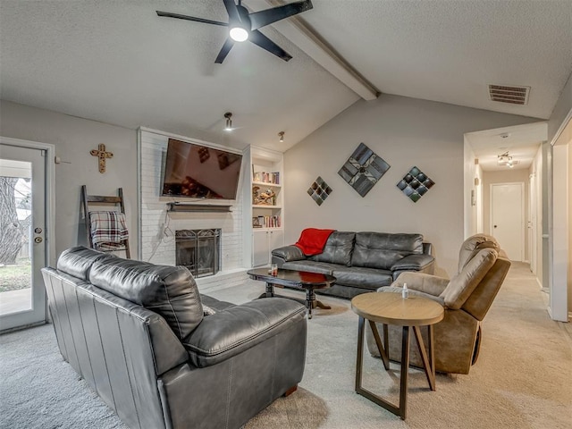 carpeted living room featuring ceiling fan, a fireplace, lofted ceiling with beams, a textured ceiling, and built in shelves