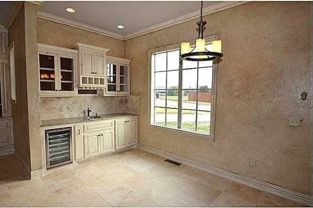 kitchen featuring sink, beverage cooler, a chandelier, hanging light fixtures, and crown molding