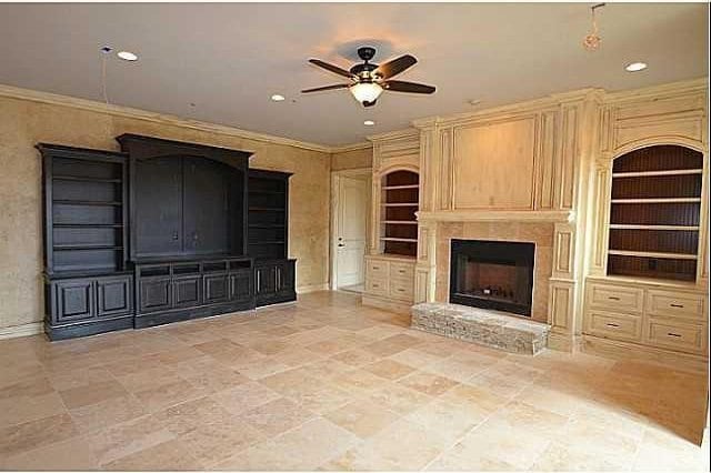 unfurnished living room with built in shelves, ceiling fan, and ornamental molding