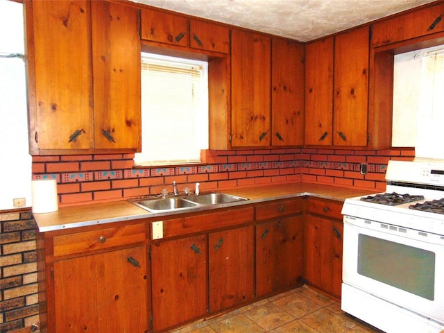 kitchen featuring white range with gas cooktop, sink, a textured ceiling, and backsplash