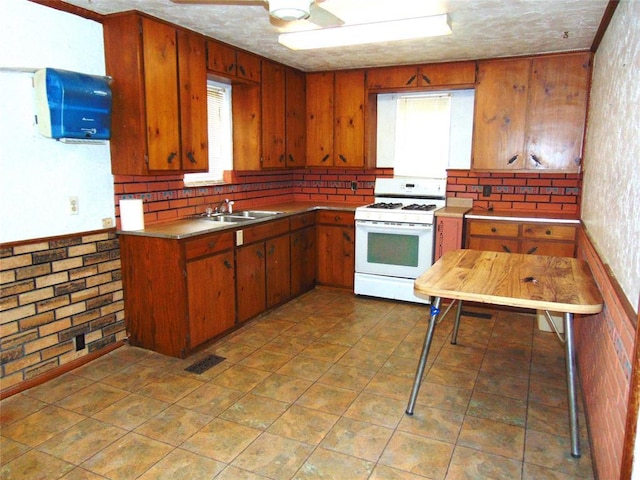 kitchen with white gas range, sink, and ceiling fan